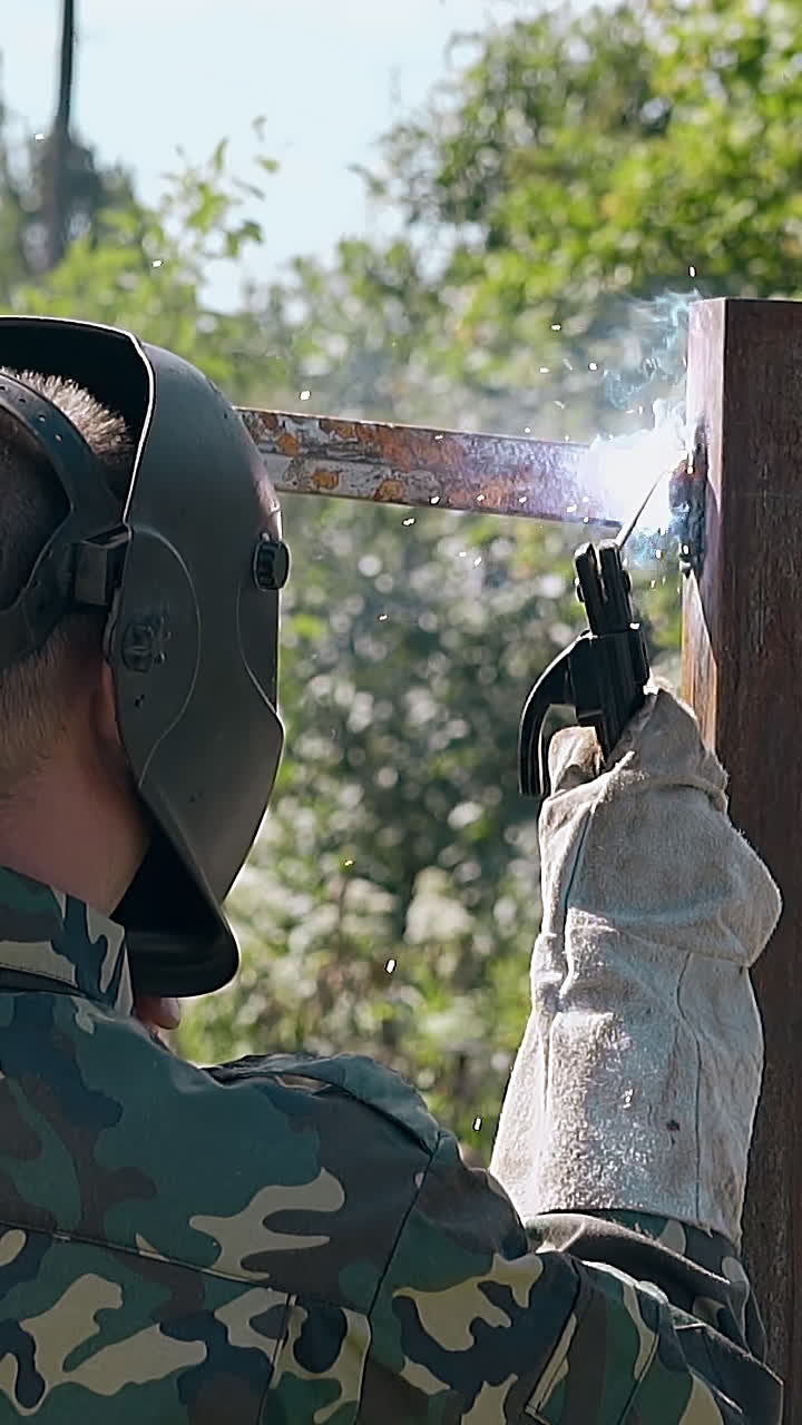 Welder repairing a metal fence