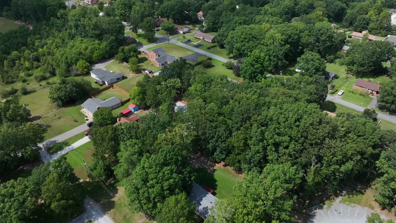 Aerial flyover American suburb neighborhood with large houses and green garden. Sunny day in summer. Quiet residential area in Virginia, USA. Top down landing shot