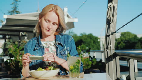 young woman takes pictures of beautiful dishes in a cafe good rest on the summer verandah and summer