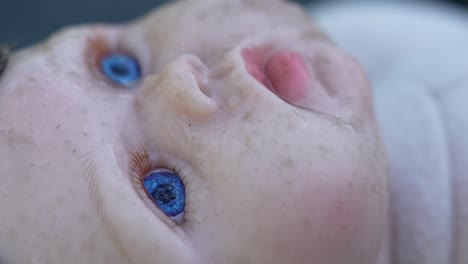 a poignant slow pan over a baby doll's face, adorned with raindrops that glisten softly. the gentle rain creates a melancholic yet soothing atmosphere, inviting viewers to reflect.