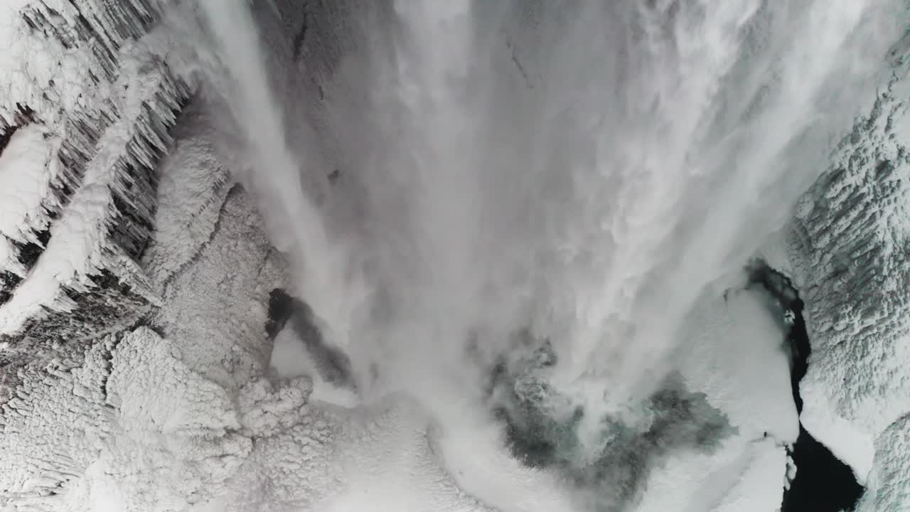 A beautiful large waterfall in Iceland in mid-winter covered by the snow around it and the clouds makes it even better