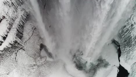 una hermosa cascada grande en islandia en pleno invierno cubierta por la nieve a su alrededor y las nubes lo hacen aún mejor
