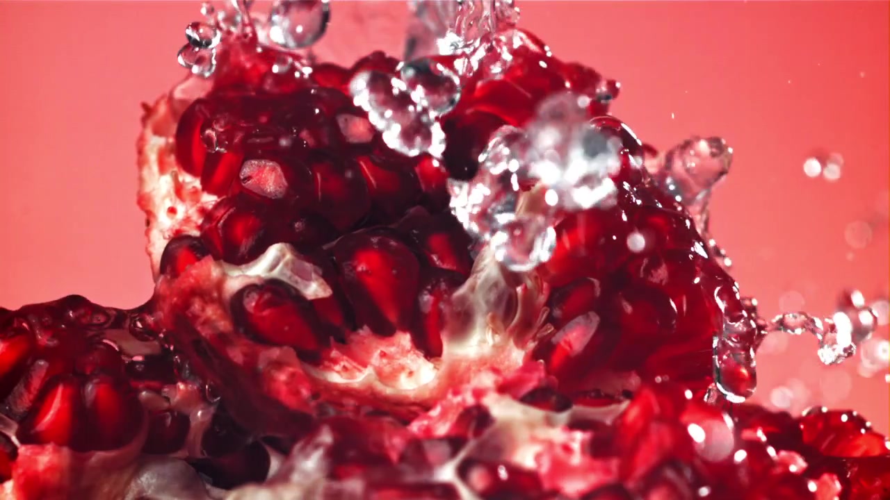 Slowmotion vand sprøjter på friske granatæblekerner