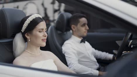 bride and groom in a white convertible car