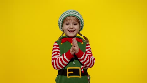 Kid-girl-Christmas-elf-Santa-helper-steepls-fingers-waiting-for-gift-box.-Child-in-New-Year-holidays