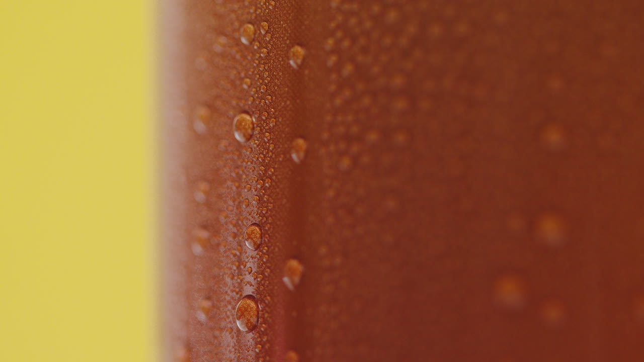 cerca de las gotas de condensación que corren por la lata de cerveza fría o refresco para llevar contra un fondo amarillo