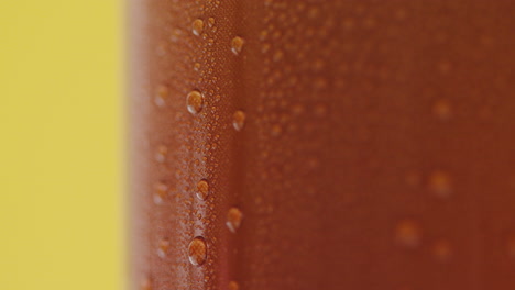 cerca de las gotas de condensación que corren por la lata de cerveza fría o refresco para llevar contra un fondo amarillo
