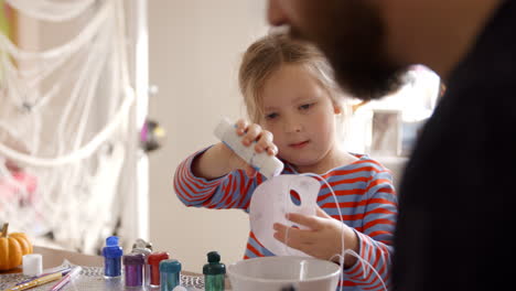 father and daughter making halloween masks at home together