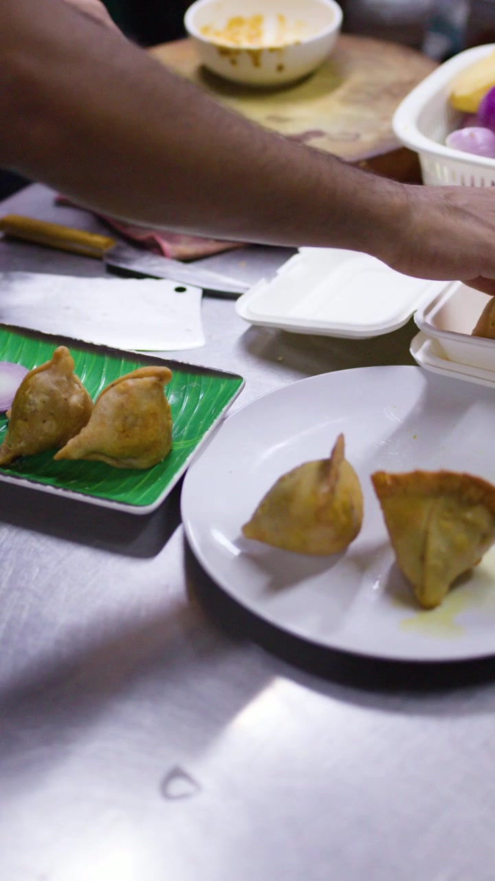 Venditore di cibo di strada che confeziona samosa appena fritte in contenitori da asporto