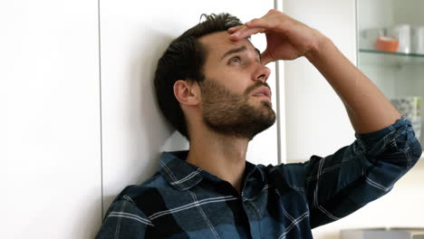 Man-is-standing-against-a-wall-with-a-sad-expression-on-his-face