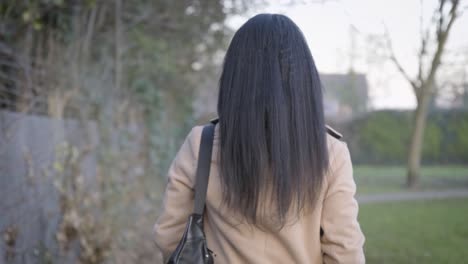 detrás de la empresaria negra caminando al trabajo en el camino del parque día nublado y frío con abrigo en el centro de la ciudad de londres