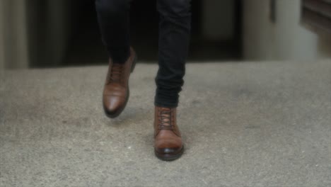 feet of a male model in brown leather boots walking on the floor. cropped shot