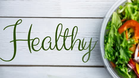 animation of healthy text in green, over fresh salad in bowl on white boards