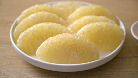 pomelo fresco pelado, pomelo o shaddock en plato blanco