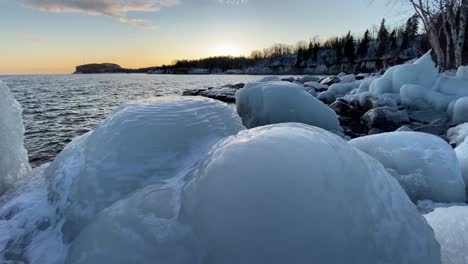 big chunks of ice, rocks covered on ice on lake superior shore line, sunset