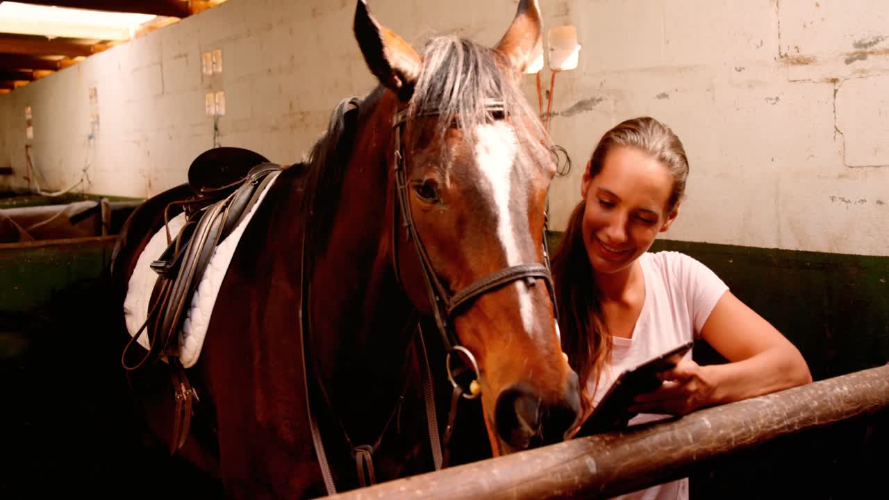 Woman standing with horse using digital tablet 4k