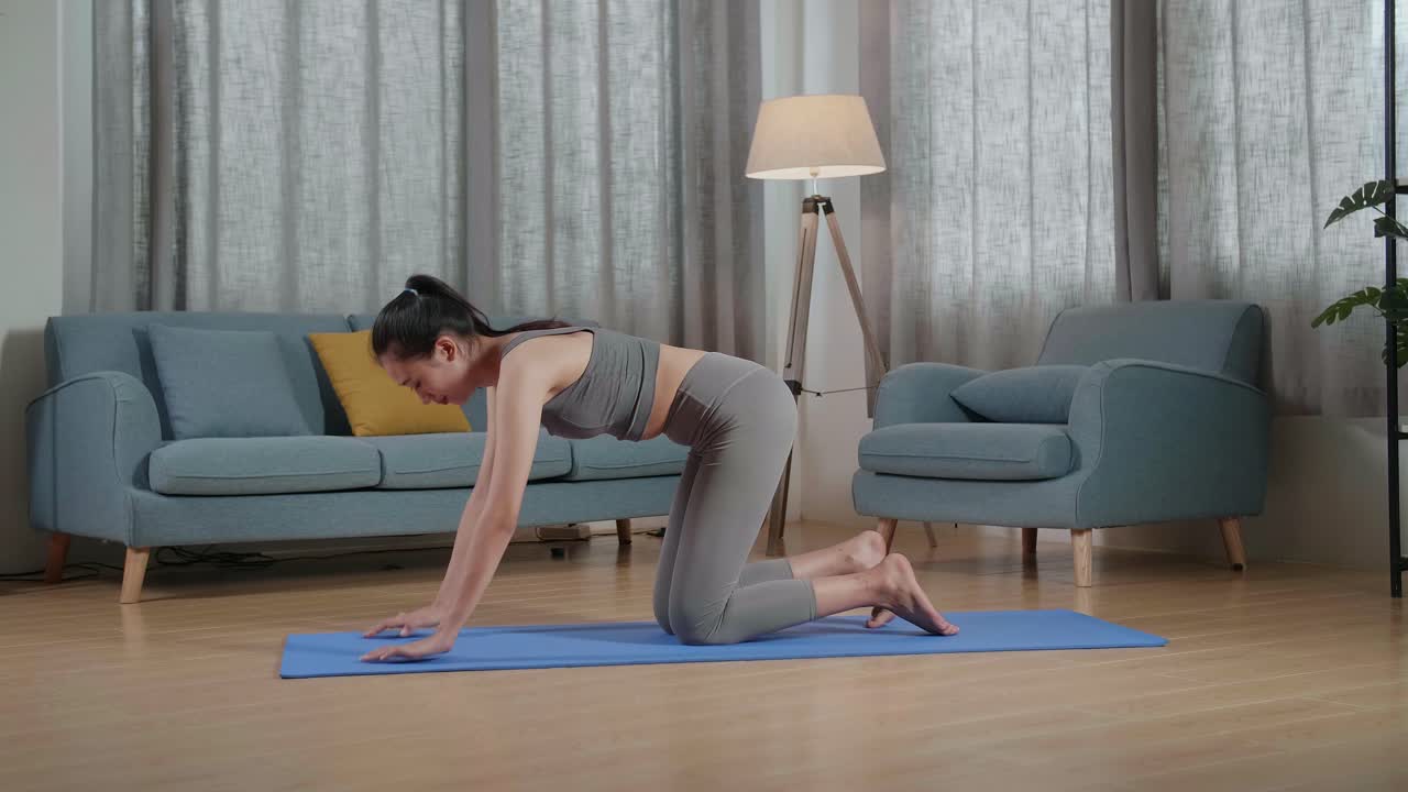 집에서 운동을 가르치는 동안 말을 하고 스트레칭하는 스포츠 옷을 입은 젊은 아시아 트레이너 여성의 전체 시각