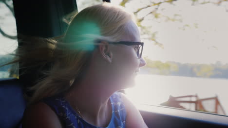 mujer feliz mirando por la ventana del auto