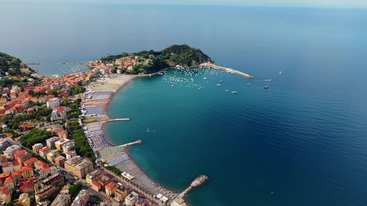 Una penisola separa due baie sabbiose a Sestri Levante mentre il drone si allontana.