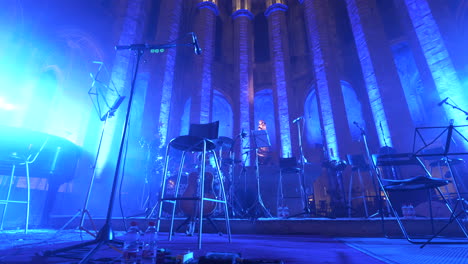 musical instrument setup on stage in barcelona cathedral lit by neon lights, motion view