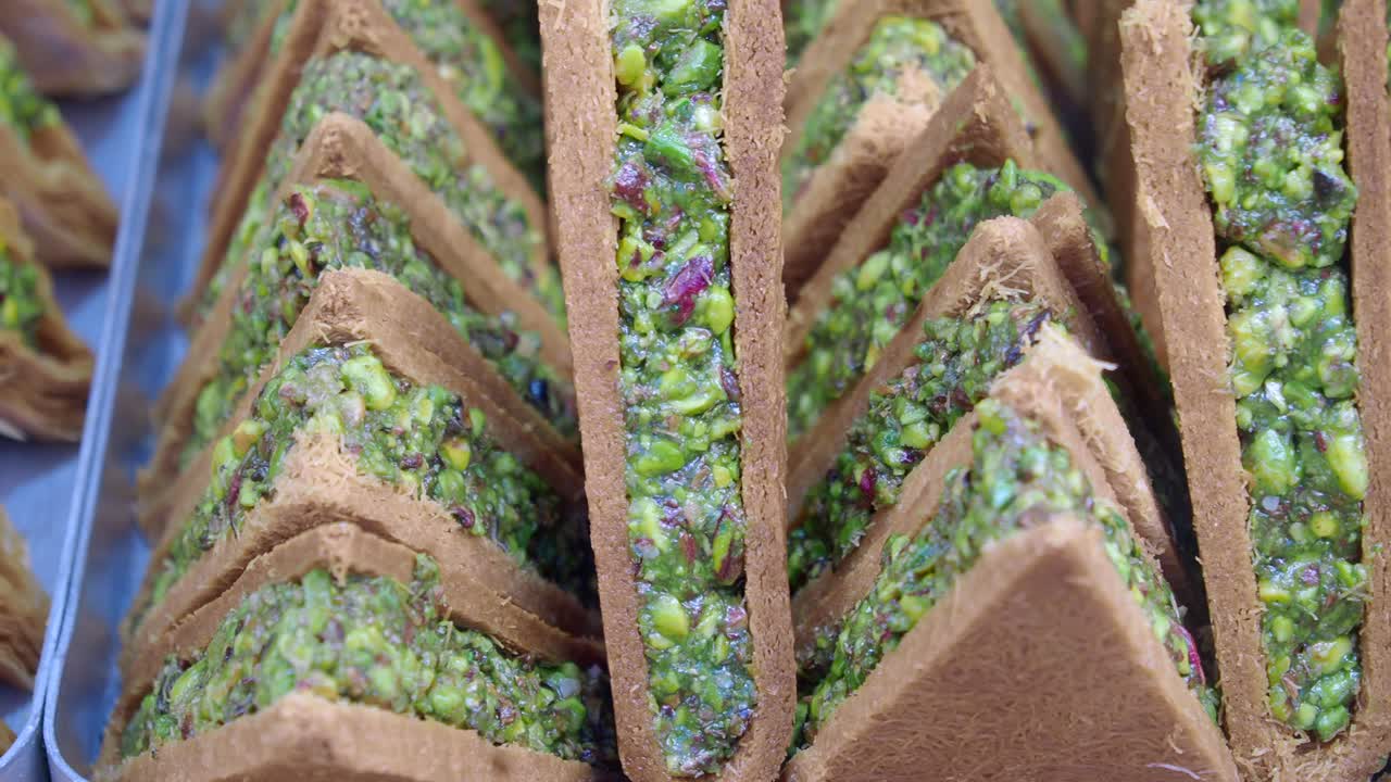 primer plano de una exhibición de baklava triangular con pistachos