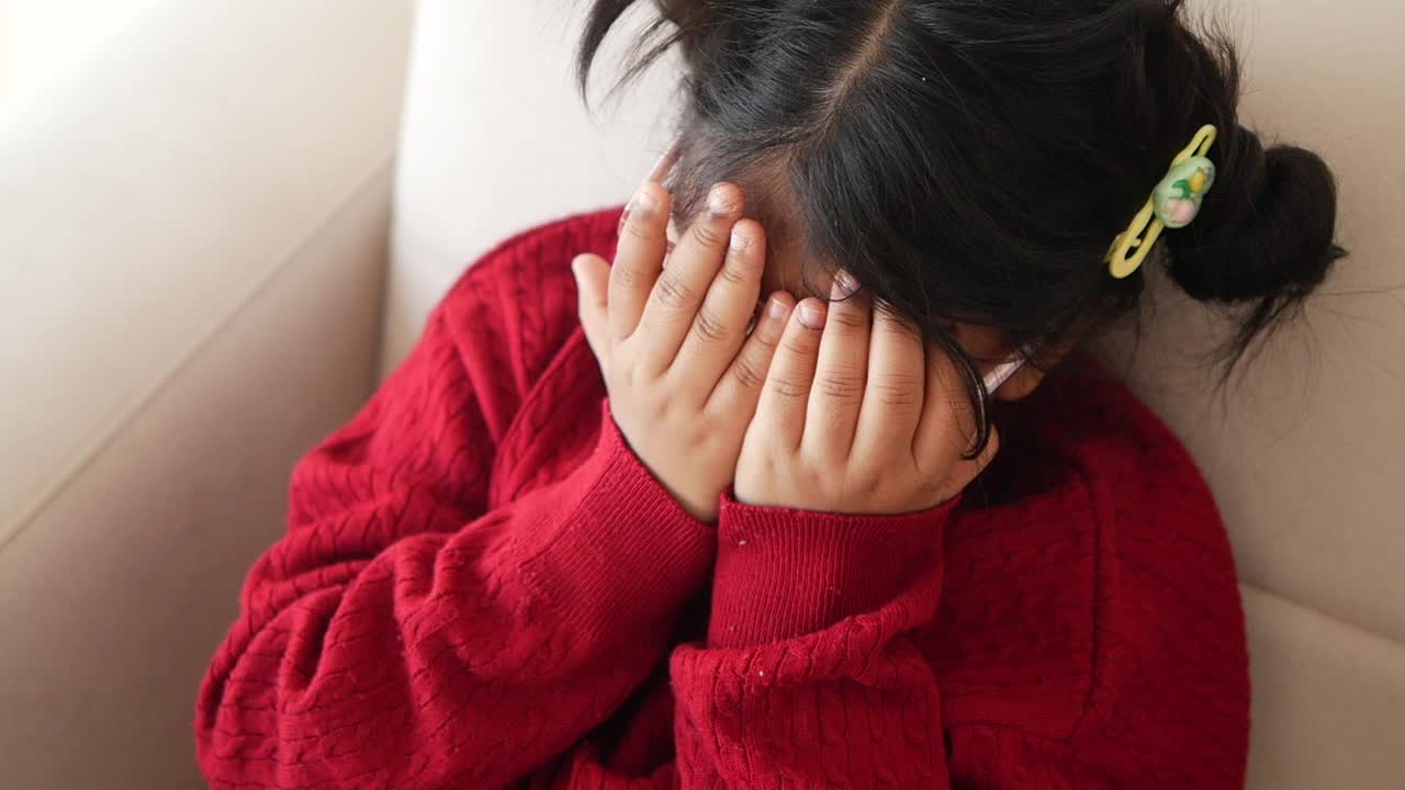 Young girl crying with her hands over her face