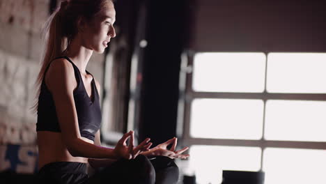 Lockdown-Aufnahme-Einer-Schönen-Jungen-Frau,-Die-Im-Lotussitz-Im-Fitnessstudio-Sitzt