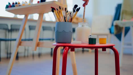 workplace of the artist. brushes, paints and water are on the table. circular motion of the camera.