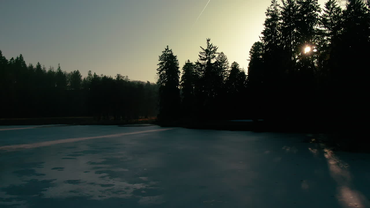 inverno lago drone volo aereo acqua ghiacciata foresta alberi di pino tramonto luce del sole raggi di luce pruhonice repubblica ceca