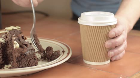 Eating-chocolate-cake-with-take-out-coffee-medium-shot