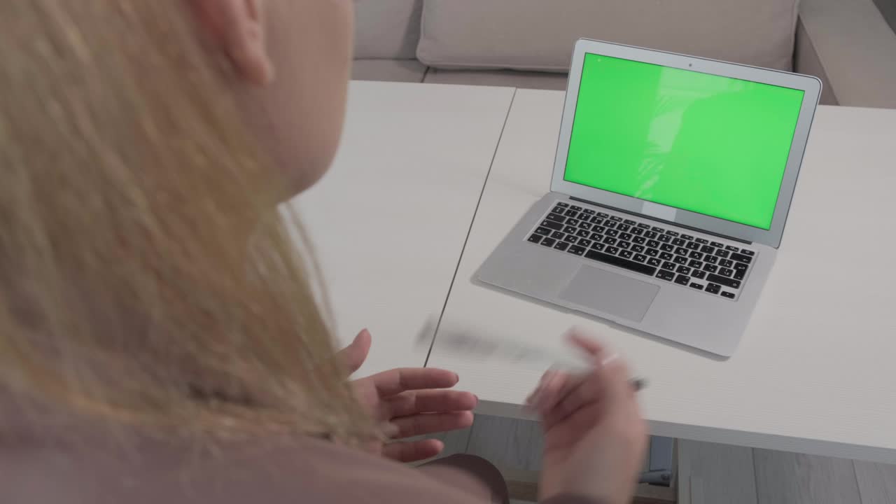 hay una computadora portátil con una pantalla verde en la mesa, un lugar para la publicidad.