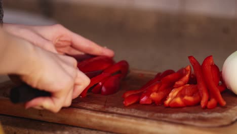 women in the yellow clothes cutting bulgarian sweet red pepper with a sharp knife for cooking