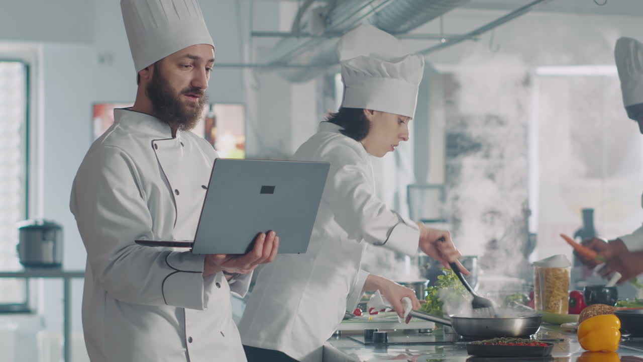 Man and woman using laptop to cook food recipe in kitchen