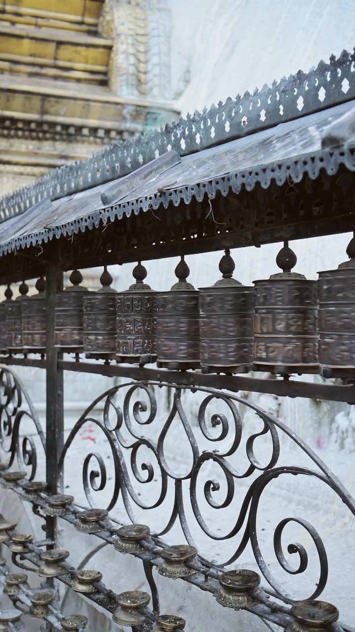 Nepal'in Katmandu şehrindeki Maymun Tapınağı'nda dikey Tibet Budist dua çarkları. Dönen dua çarklarının sosyal medya Instagram Reels ve TikTok için dikey videosu, dua etmek için dini bir sembol.
