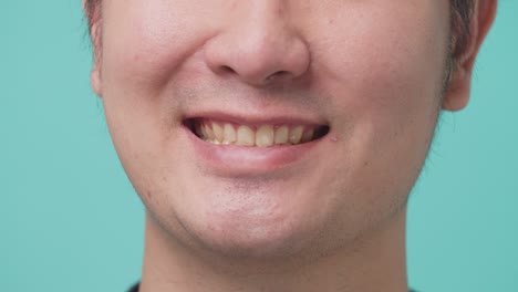 close up of portrait of attractive asian young man smiling and laughing in studio with isolate green screen in background. the man feeling happy and cheerful with positive attitude and thinking.