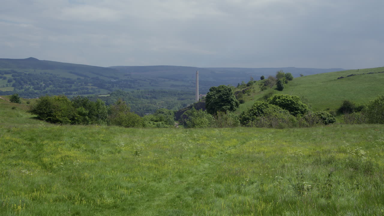 tomada amplia de campos abiertos con chimenea de fábrica y la gran cresta en el fondo tomada en siggate road