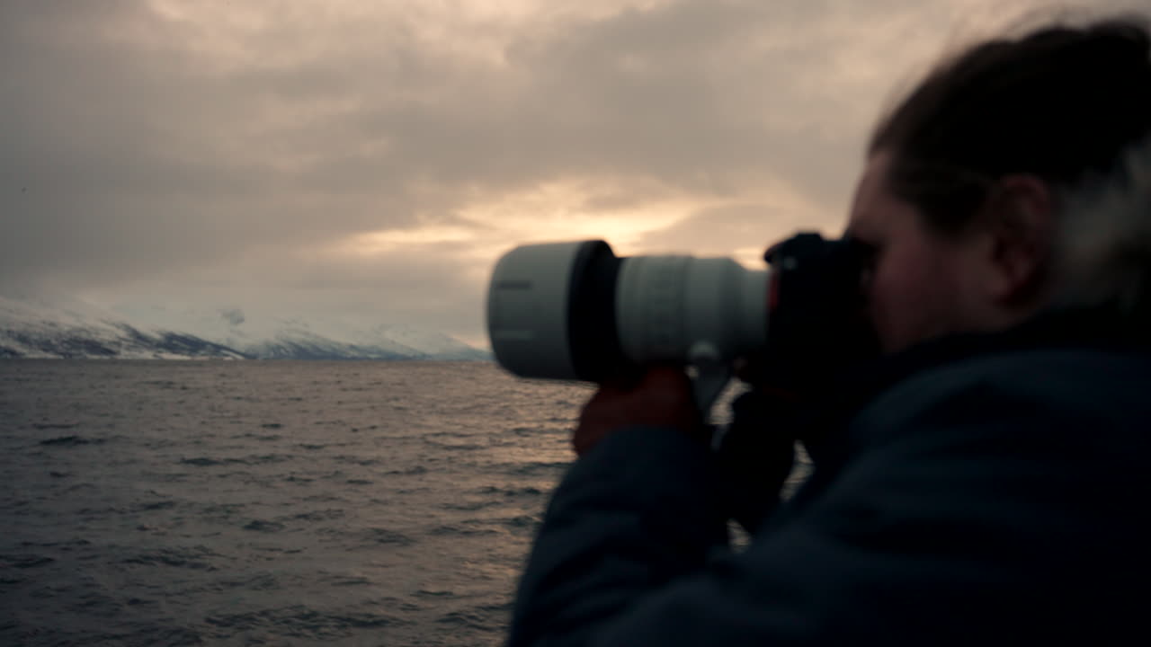 hombre en un paseo en barco capturando una escena de ballena con una cámara al atardecer. observación de ballenas en skjervoy, noruega. primer plano, toma amplia