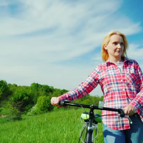 the cyclist's hands on the handlebars of the bike rides in a picturesque place against the backdrop of a green meadow or field