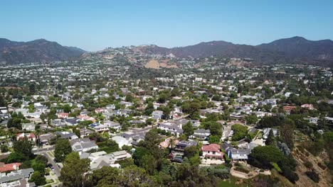aerial tilt up shot of luxury american neighborhood with swimming pool and palm trees. housing area with mansions in pacific palisades, california, usa. wide shot.