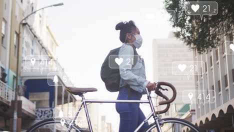 Animation-Von-Social-Media-Texten-Und--Symbolen-über-Einer-Gemischtrassigen-Frau-Mit-Gesichtsmaske-Und-Fahrrad-In-Der-Stadt