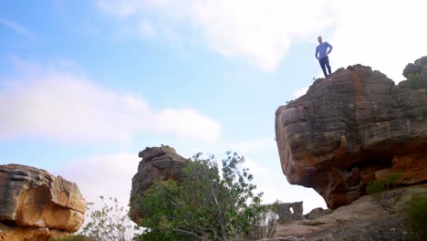 excursionista masculino de pie en la cima de una montaña rocosa 4k