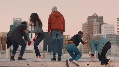 diverse-group-of-friends-on-rooftop-celebrating-friendship-with-arms-raised-enjoying-hanging-out-together-drinking-alcohol-embracing-freedom-looking-at-beautiful-city-skyline-at-sunset