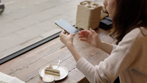 woman taking a photo of cake at a cafe