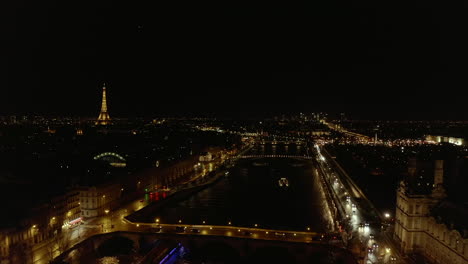 Vista-Panorámica-Aérea-De-La-Ciudad-Nocturna.-Tráfico-En-La-Carretera-Alrededor-Del-Río-Sena.-Cono-De-Foco-En-La-Parte-Superior-De-La-Torre-Eiffel-En-La-Distancia.-París,-Francia