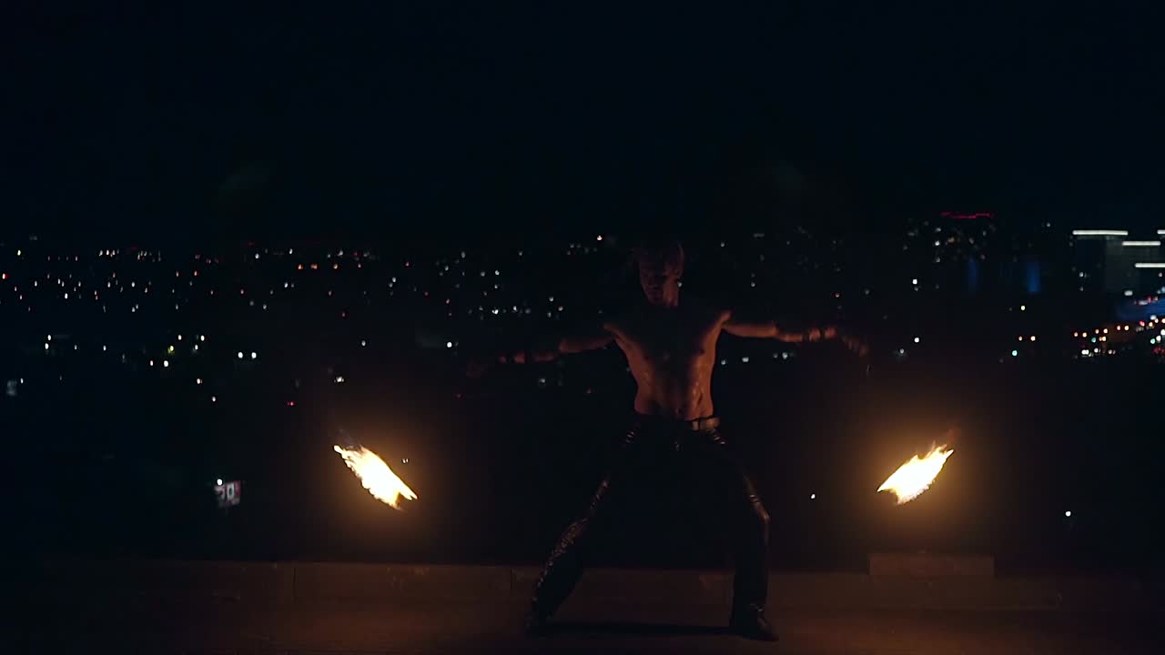 un joven hombre rubio gira dos venenos ardientes en cámara lenta