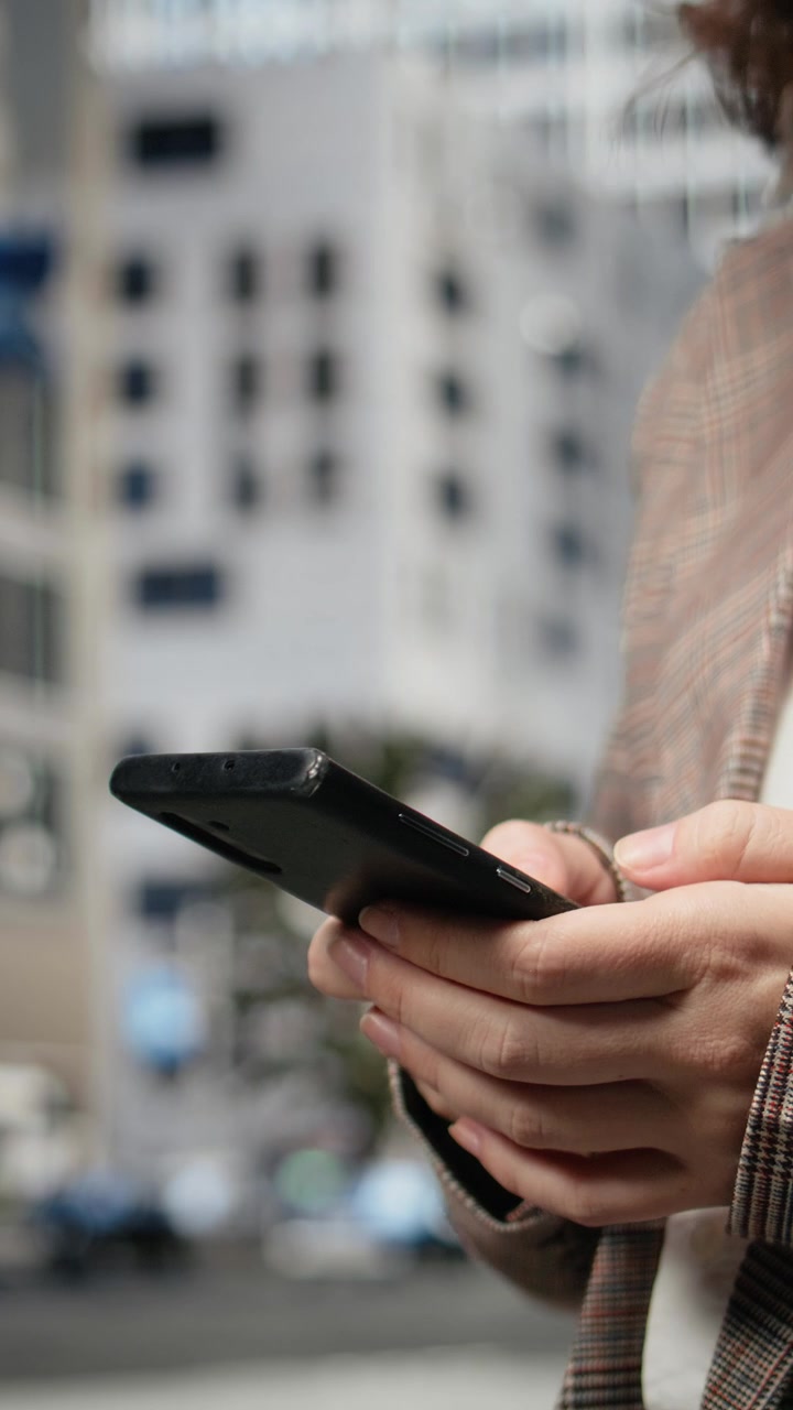 Video verticale. Primo piano di una donna d'affari che digita sullo schermo dello smartphone all'aperto