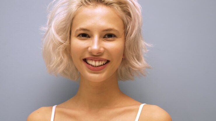 Giovane donna sorridente con capelli biondi corti