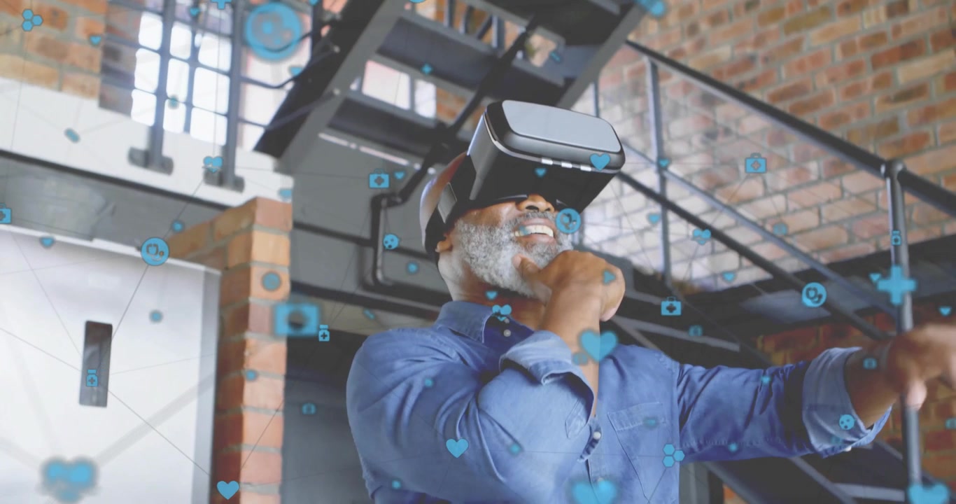 Mature man putting on VR headset in loft, materializing floating icons tapping to view health data