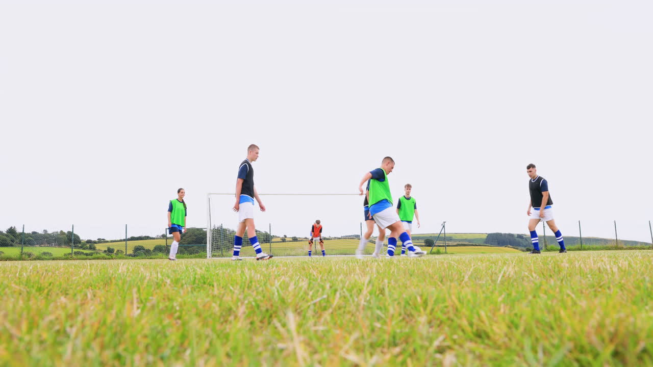 Male and female soccer players playing soccer, goalkeeper passing ball on pitch, copy space