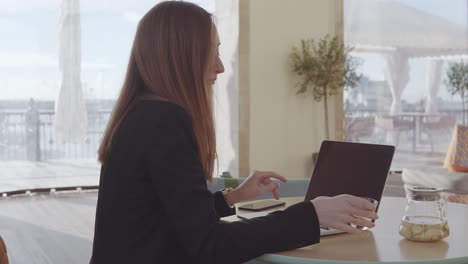 mujer trabajando en una computadora portátil en un café